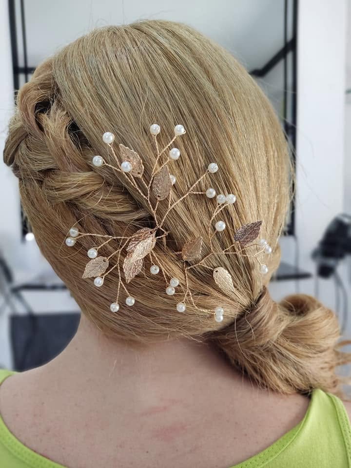 Braided low bun updo finished with a gold and pearl leaf hairpiece