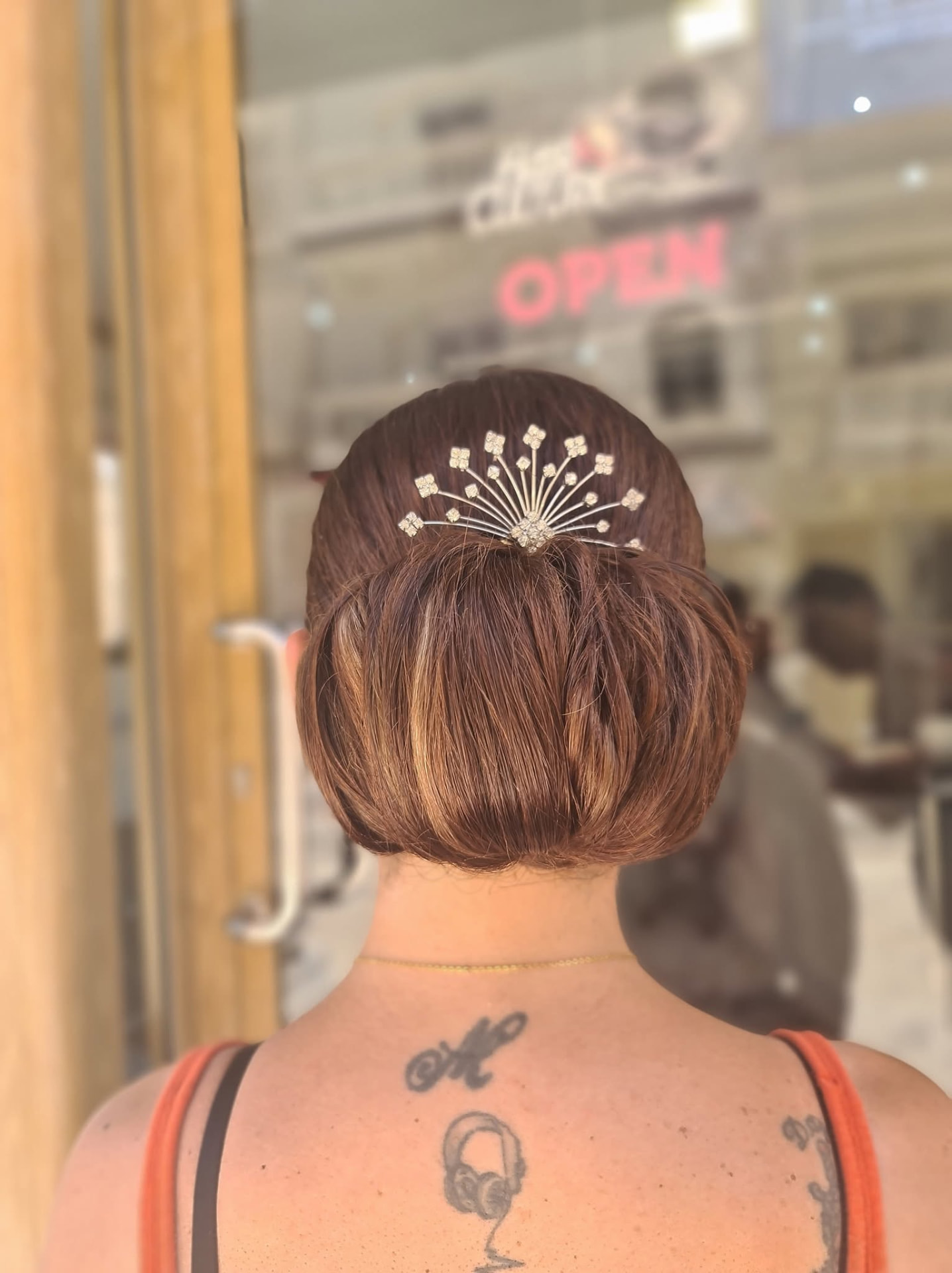 Sleek chestnut chignon bun with a crystal hair comb outside the salon